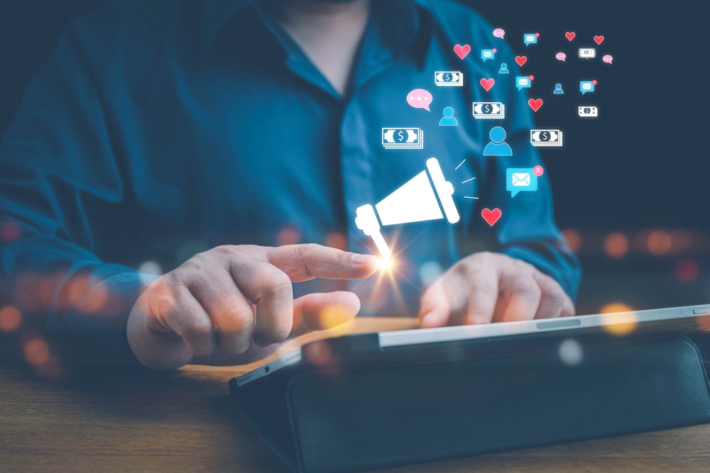 a man tapping a finger on a smart tablet with social media icons floating up from the screen